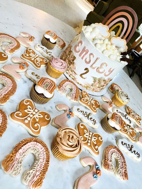 Boho second birthday spread with cake, rainbow cookies and cupcakes